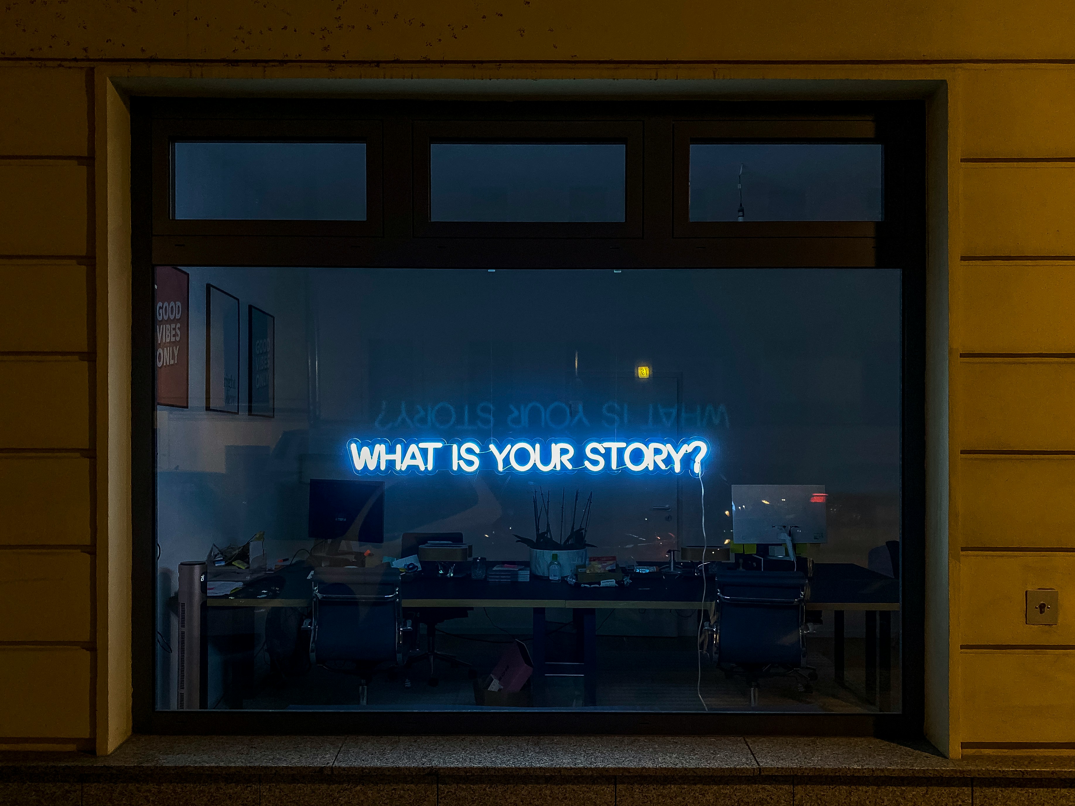 Une devanture de magasin, avec un texte en néons "What is your story?"