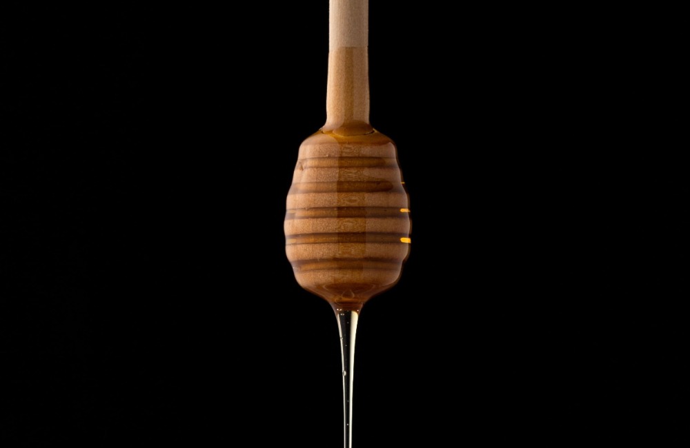 Miel qui coule d'une cuillère en bois