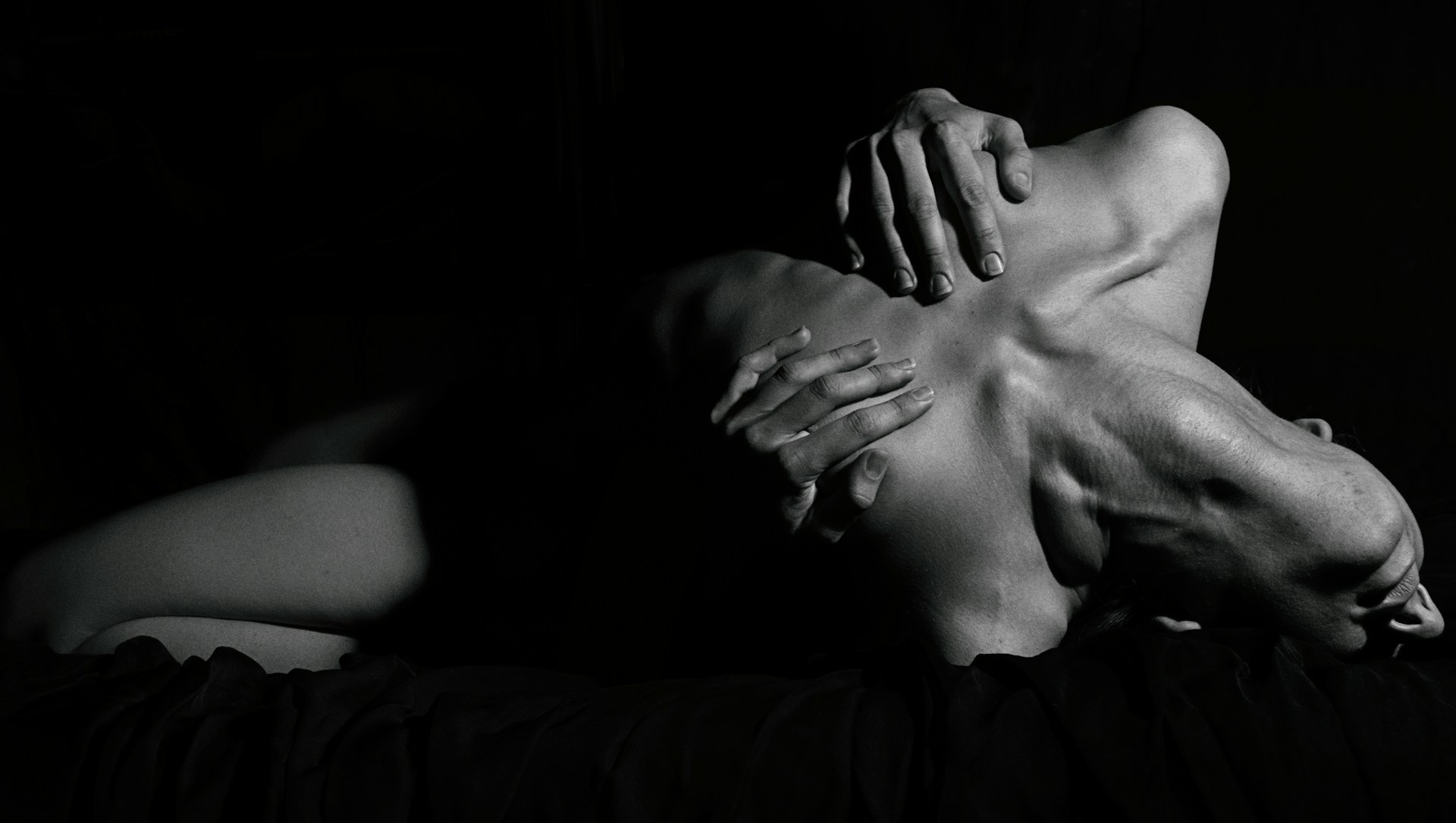 Photo en noir et blanc d'une femme cambrée prenant de plaisir en saisissant sa poitrine